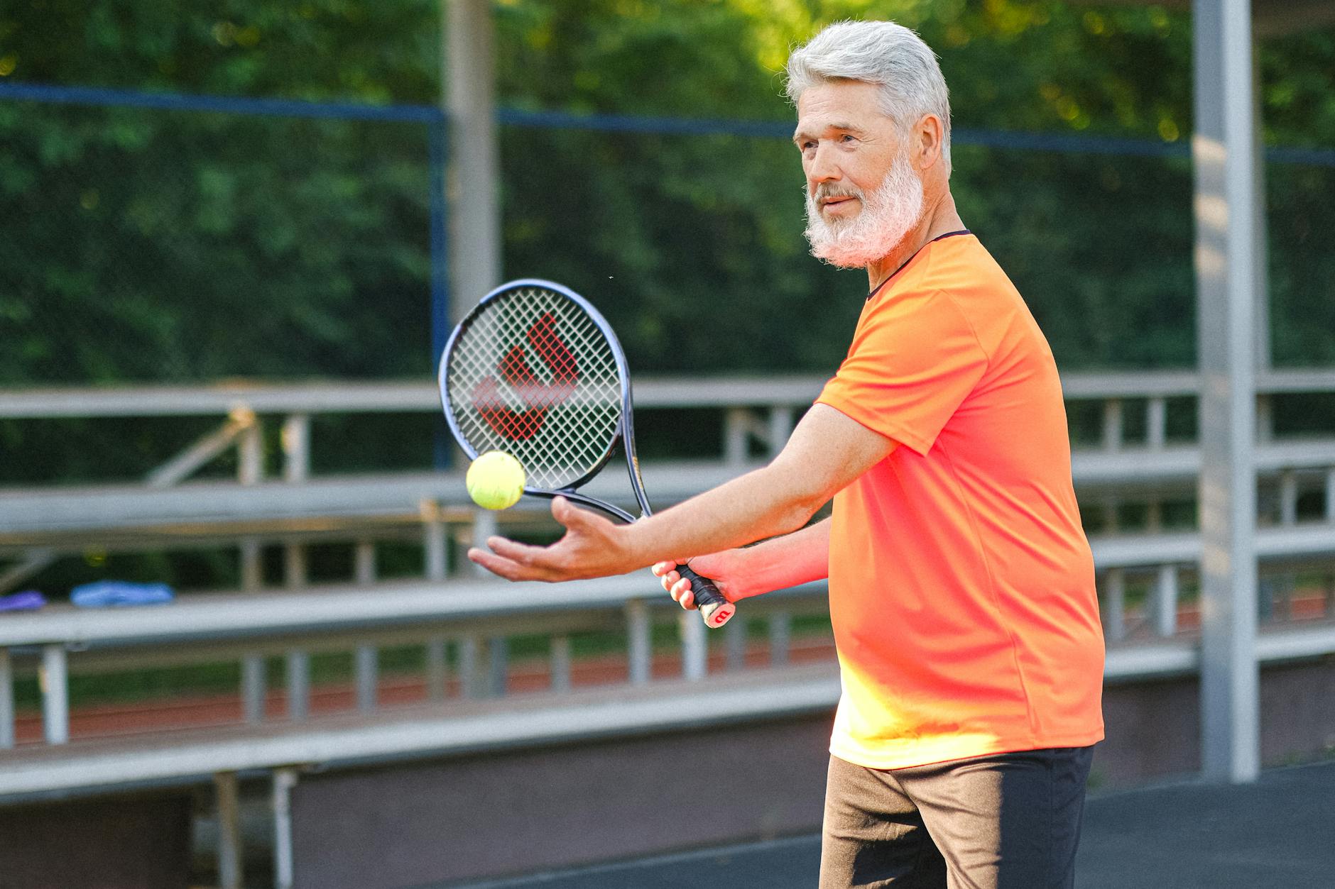 aged tennis player with ball and racket