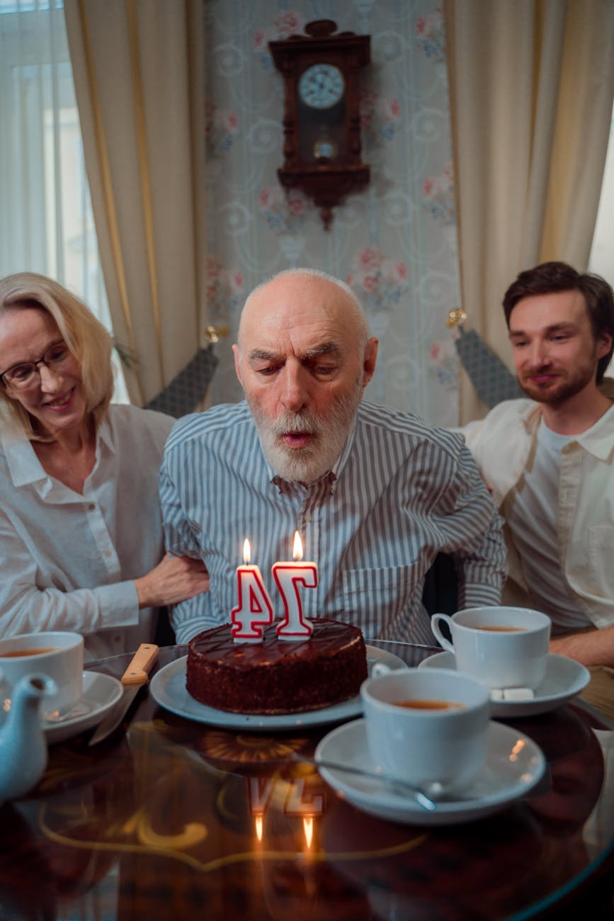 an elderly man blowing candles on his birthday cake