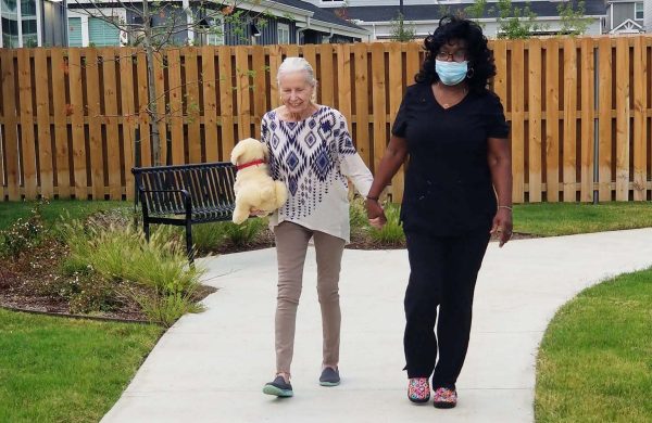 Sage Oak of Denton | Senior woman walking with caregiver outside